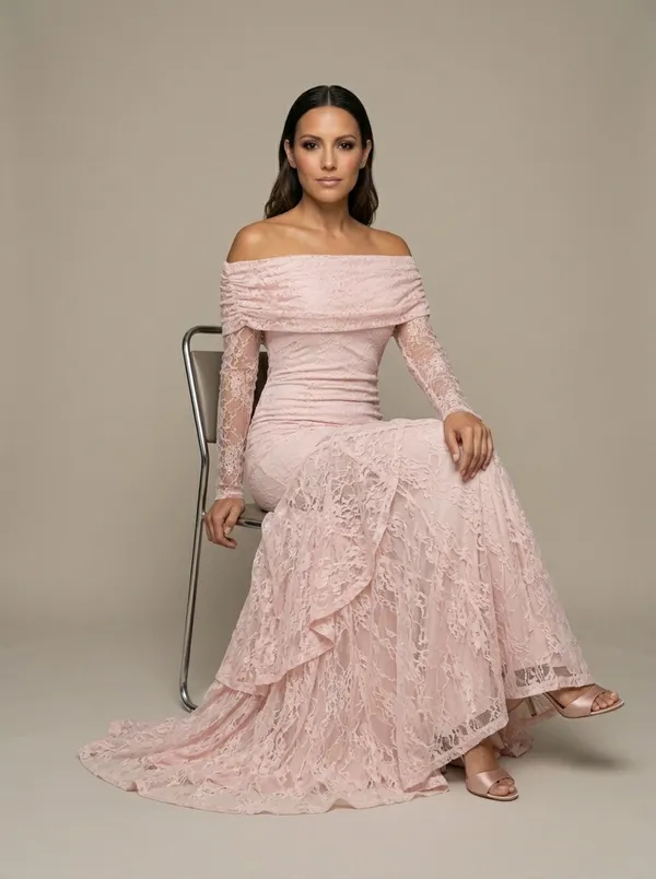 the same blush lace gown seated on a stool, the skirt spread across the floor